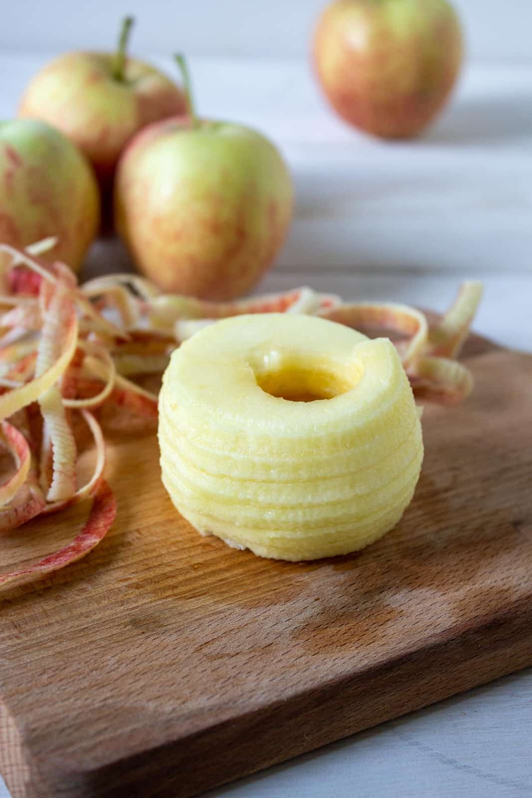 A peeled and cored apple on a small wooden cutting board.