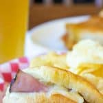 A sandwich in a basket with potato chips.