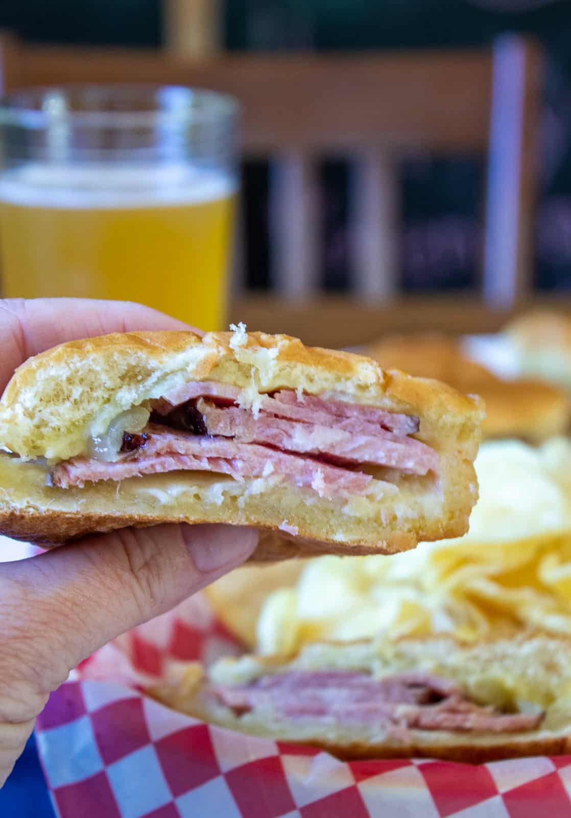 Half a baked ham and cheese sandwich held in one hand.