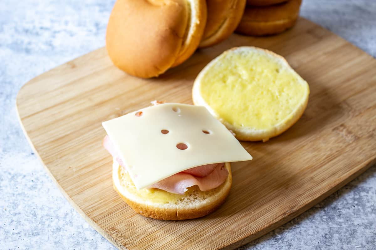 A slice of swiss cheese on top of ham on a bun.