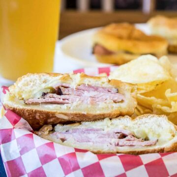 A ham sandwich on a hamburger bun cut in half.