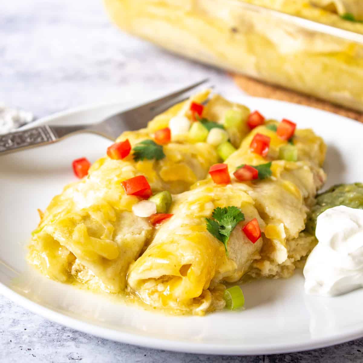 Two enchiladas with green sauce on a plate.