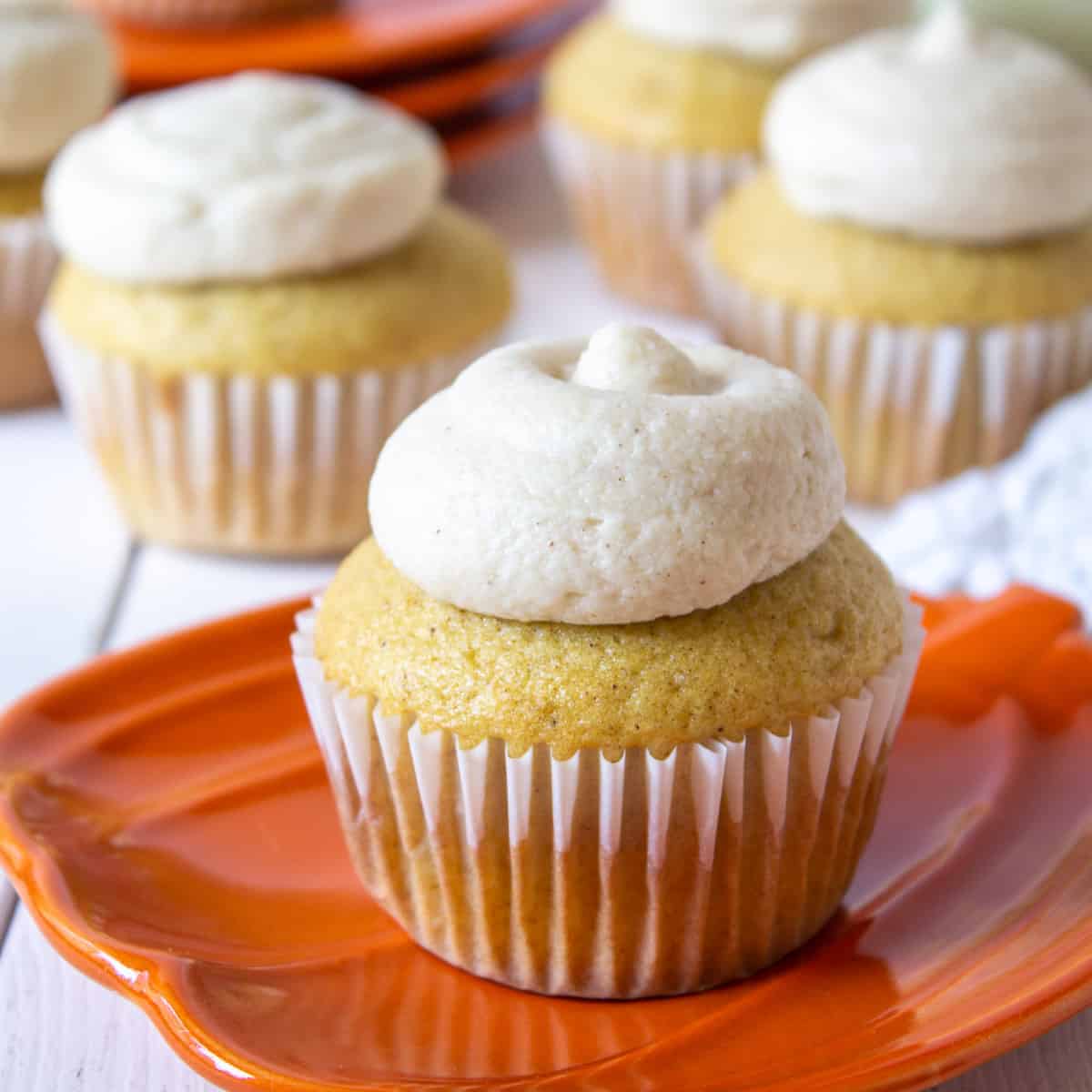 A spiced cupcake on an orange pumpkin shaped plate.