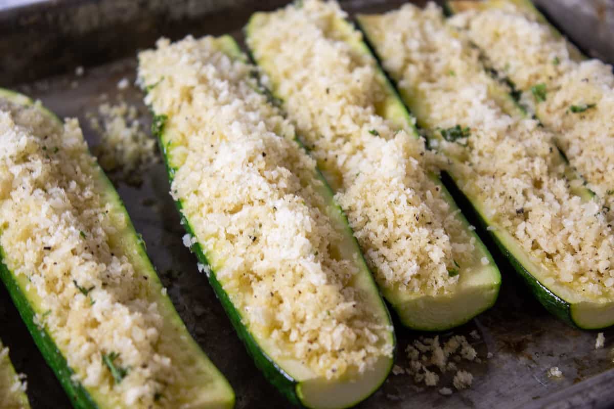 Unbaked stuffed zucchini on a baking sheet.