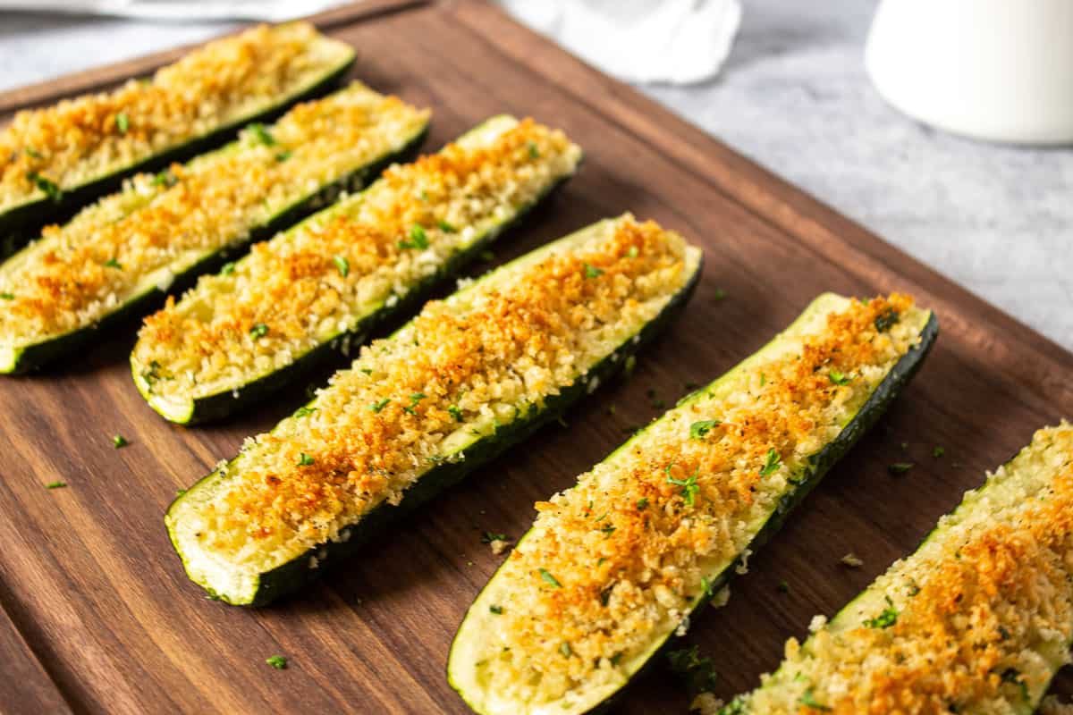 Oven roasted stuffed zucchini on a wooden cutting board.