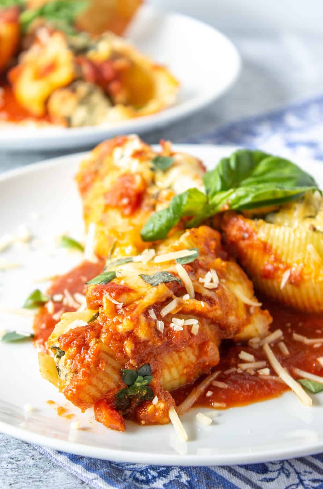 Spinach stuffed shells on a plate with marinara sauce and topped with fresh basil.