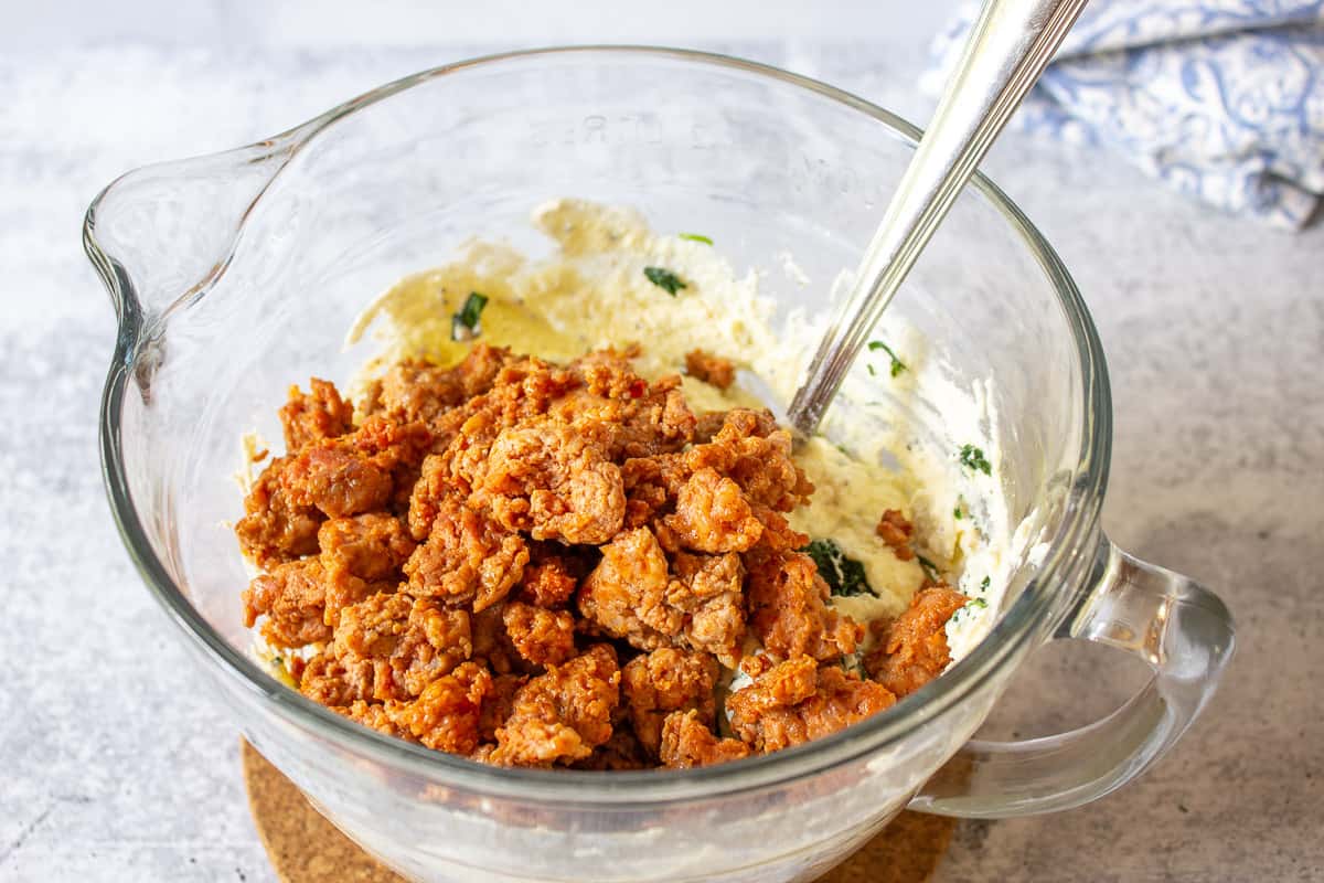 Italian sausage added to a bowl with cheese and spinach.