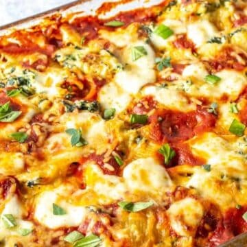 A casserole dish filled with stuffed pasta and topped with fresh herbs.