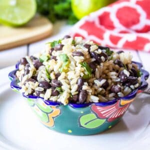 A colorful bowl filled with brown rice and black beans topped with fresh cilantro.