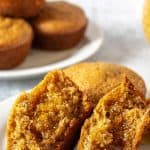 Bran muffins on a white plate with one muffin split in half and covered with honey.