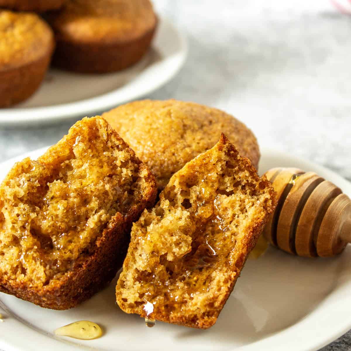 Bran muffin split in half and drizzled with honey on a white plate.