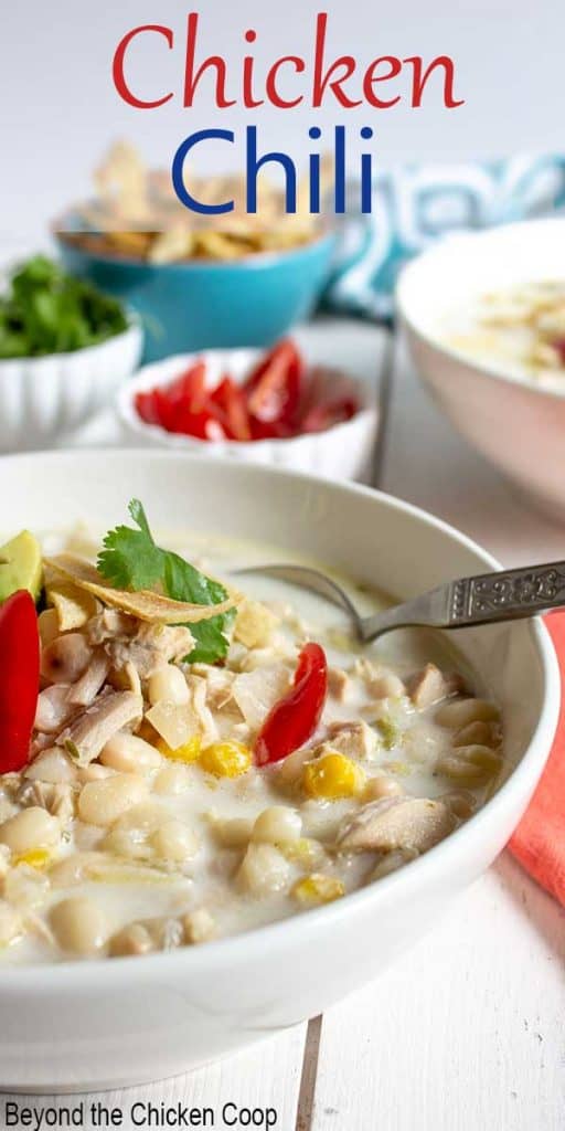 A white bowl filled with white chicken chili topped with fresh tomatoes.