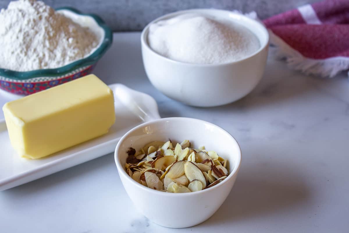 Butter, almonds, sugar and flour on a white board.