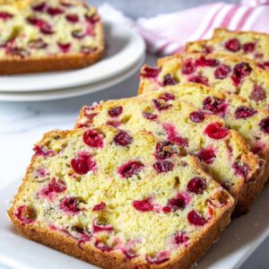 Slices of cranberry bread overlapping each other on a white tray.