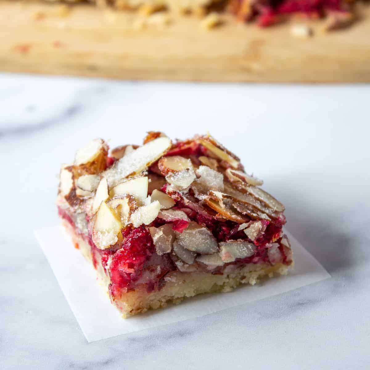 A cookie bar with cranberries and topped with almonds.