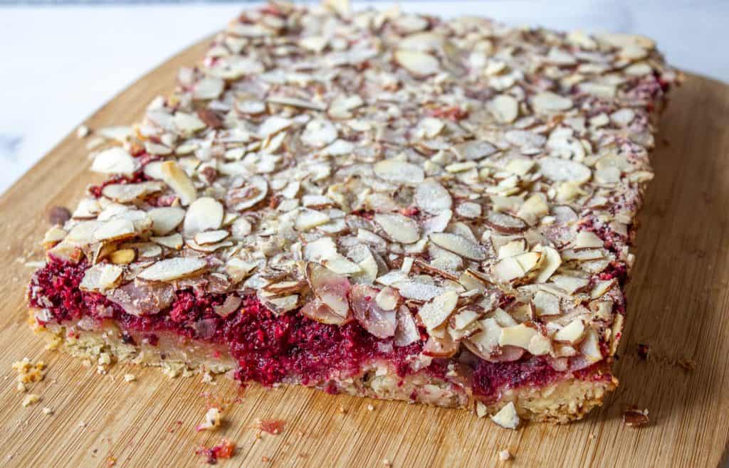 A large slab of cranberry bars on a wooden cutting board.