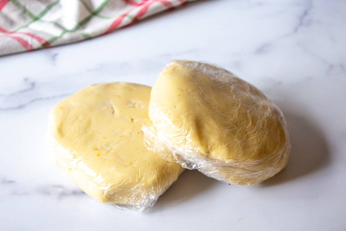 Cookie dough formed into two disks and wrapped in plastic wrap.