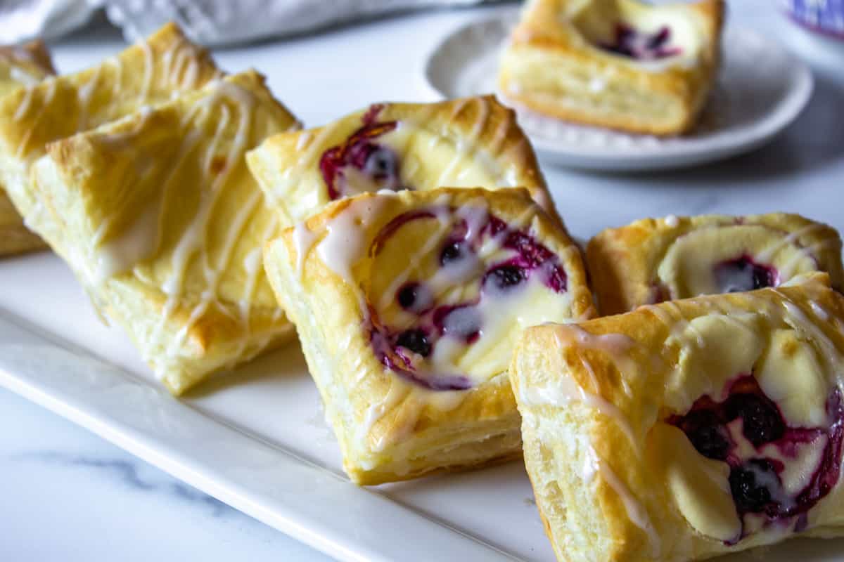 Cream cheese danishes with berries on a white platter.