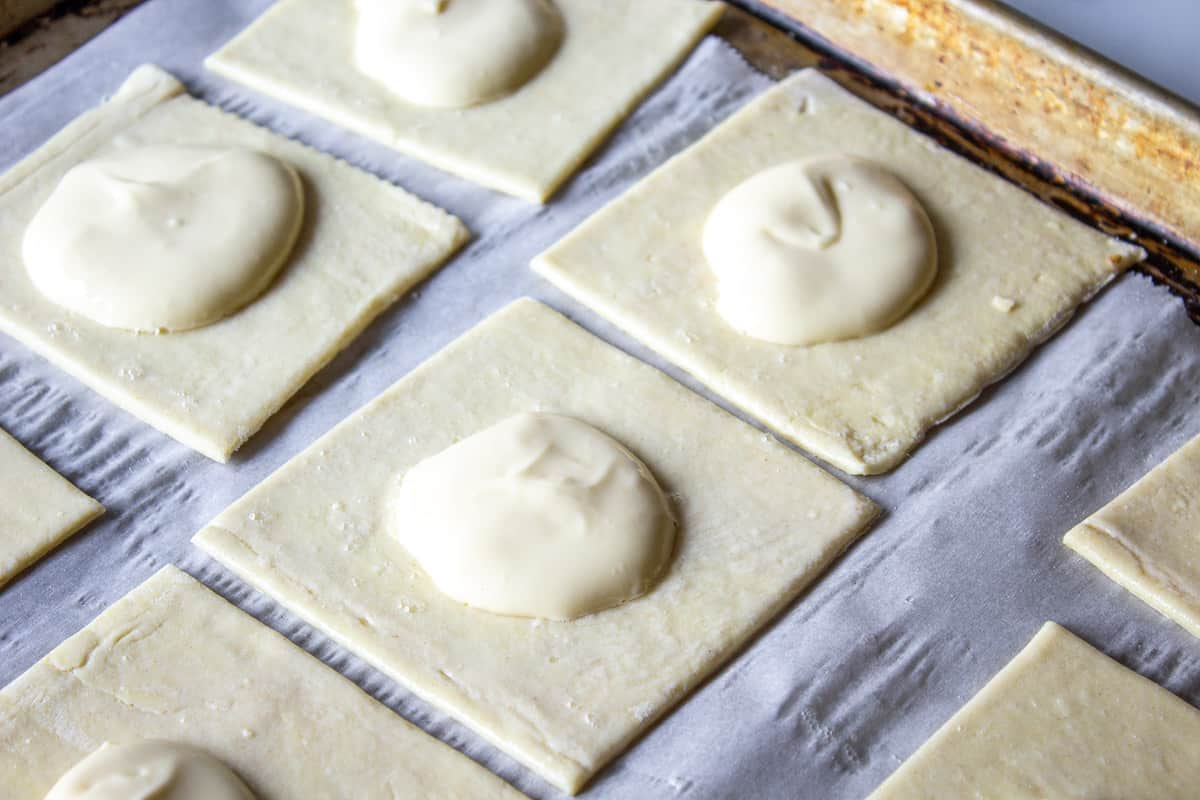 Cream cheese mixture added to the top of uncooked puff pastry squares.