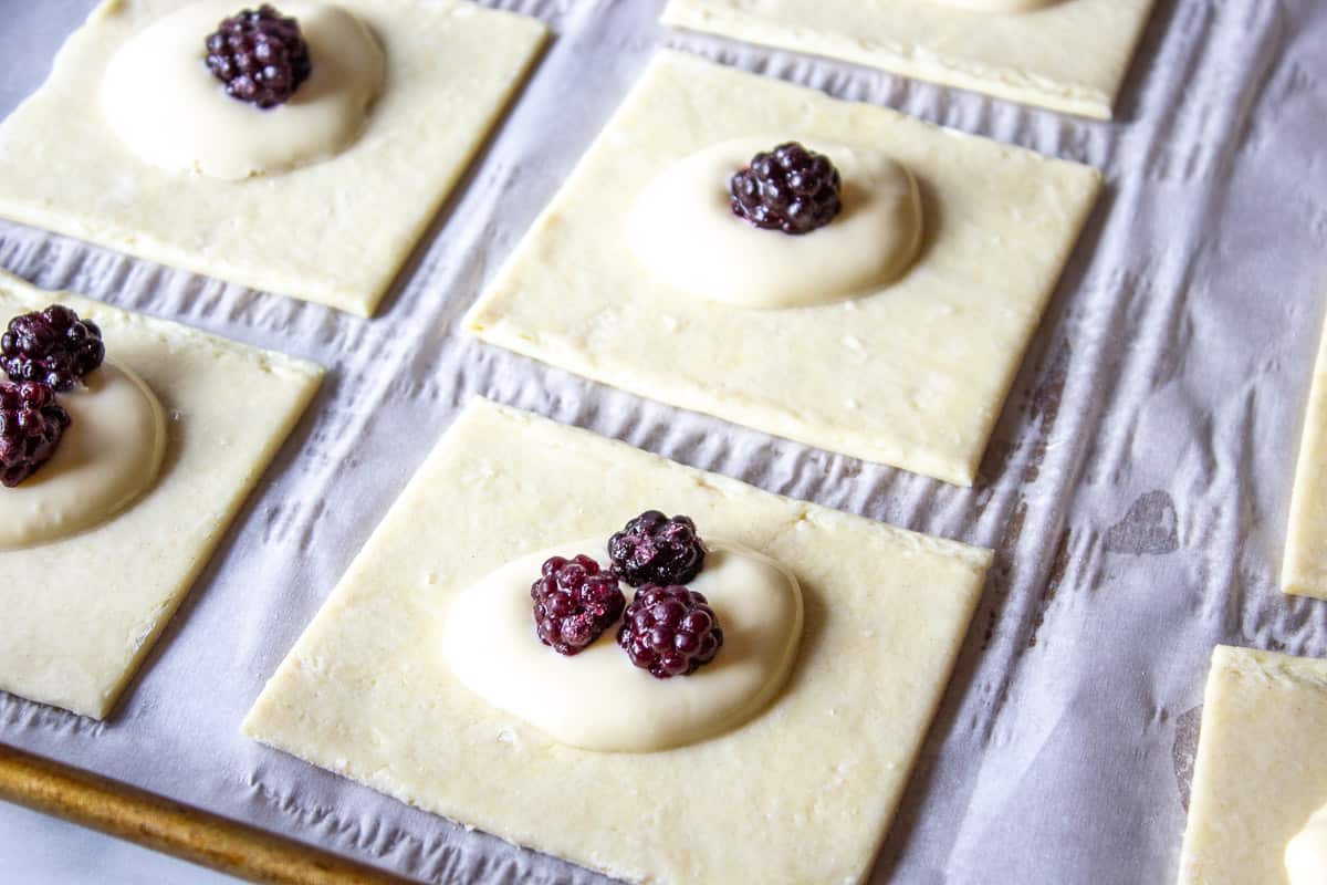 Frozen black berries on top of unbaked danishes.