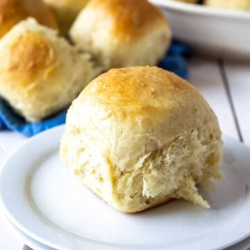 A round shaped dinner roll on a white plate.