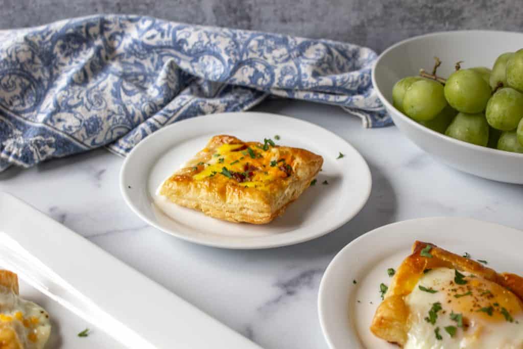 Baked eggs in puff pastry on a white plate. 