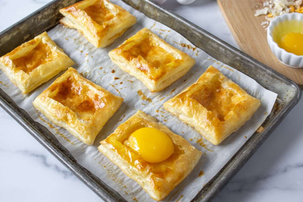 Puff pastry shells with a raw egg in one of the shells.