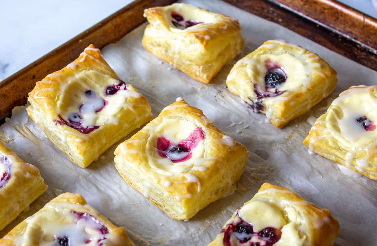 A baking sheet filled with danishes with cream cheese and berries.