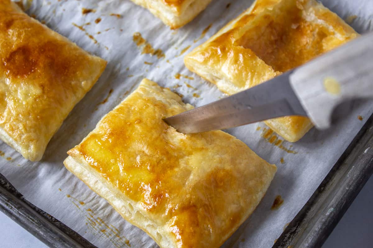 A knife slicing into a cooked pastry.