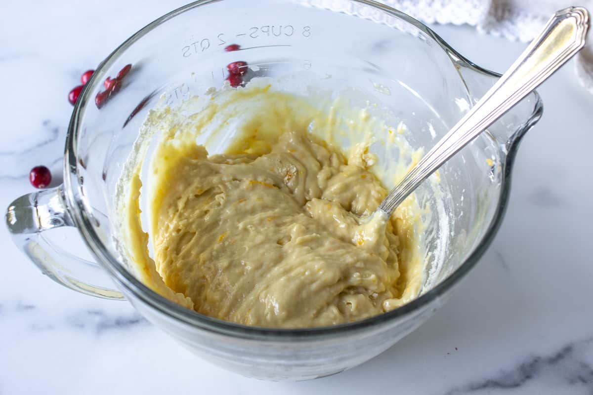 Quick bread batter in a glass bowl with a metal spoon.