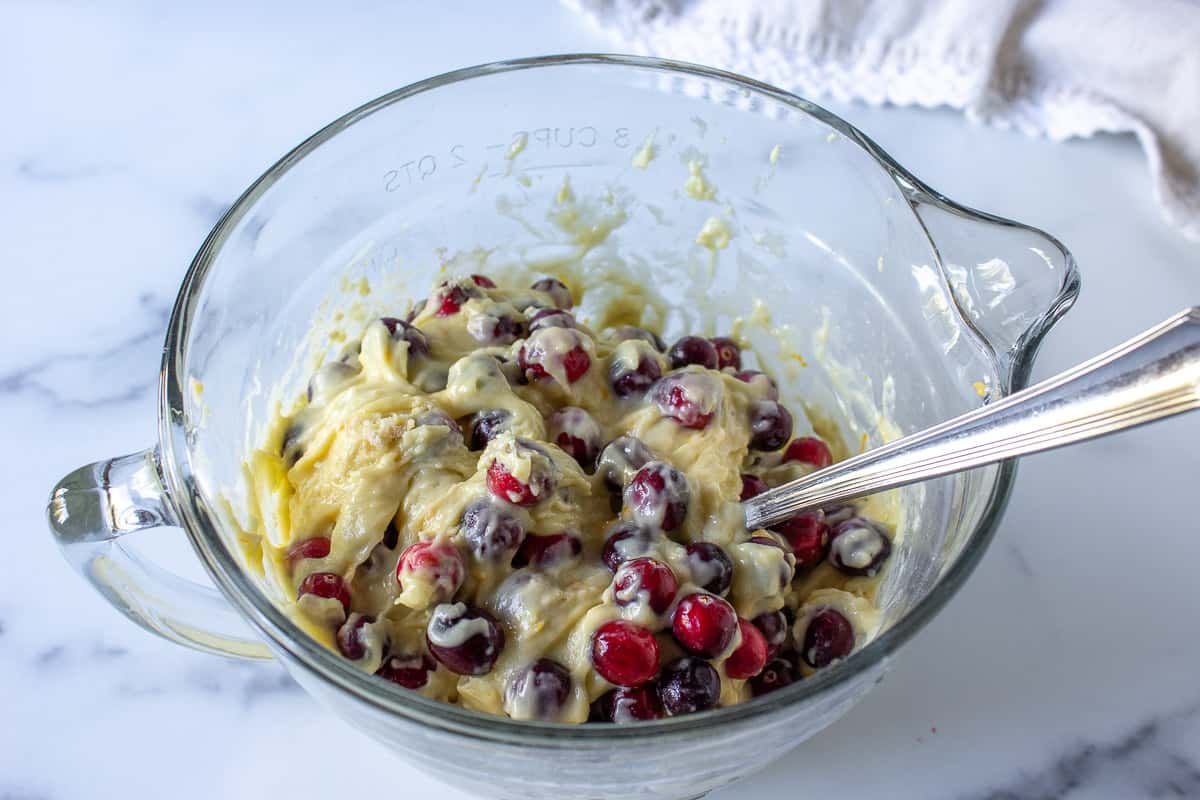 Fresh cranberries being stirred into a quick bread batter.