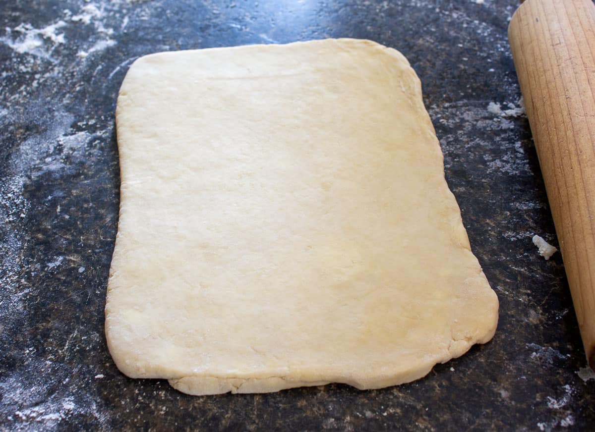 Rolled out dough on a black surface.