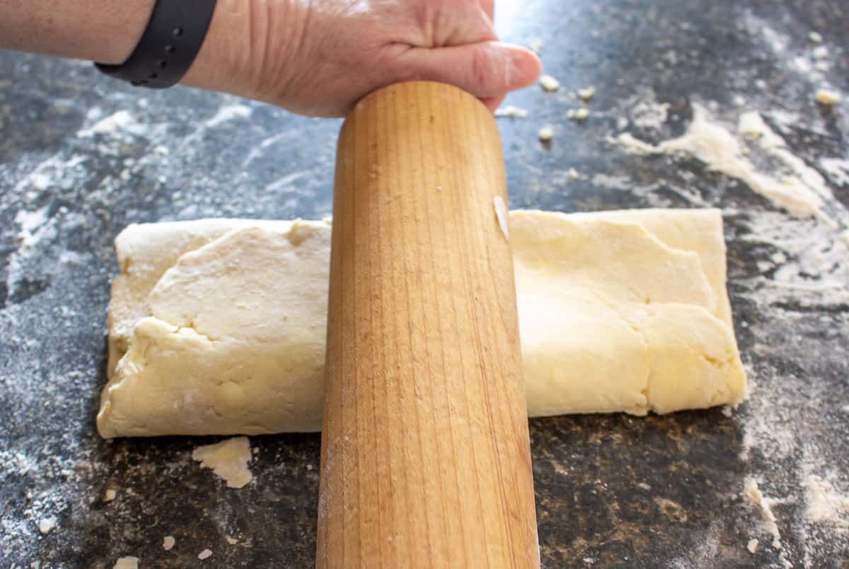 Rolling out pastry dough with a wooden rolling pin.