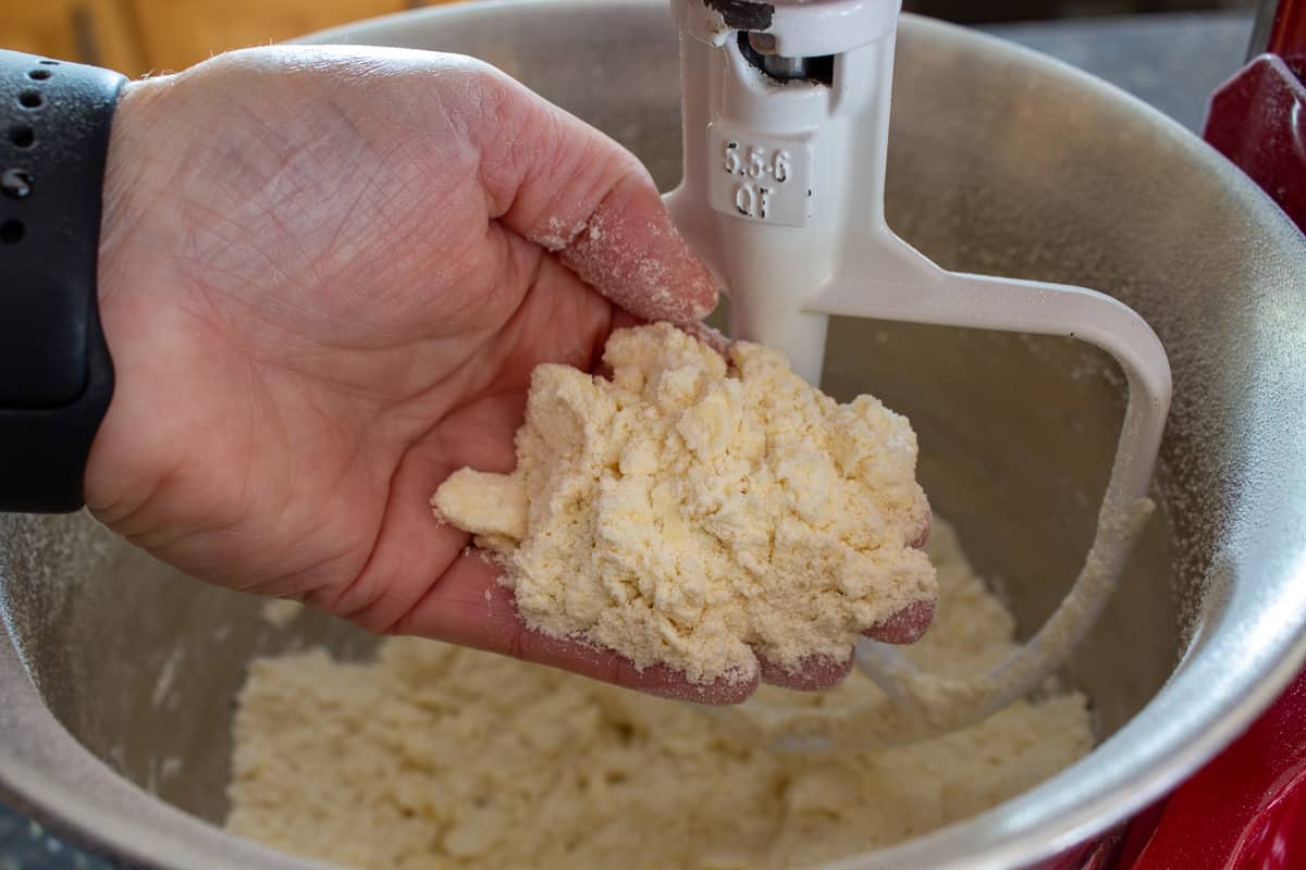 Dry flour mixture in a hand over a mixing bowl.