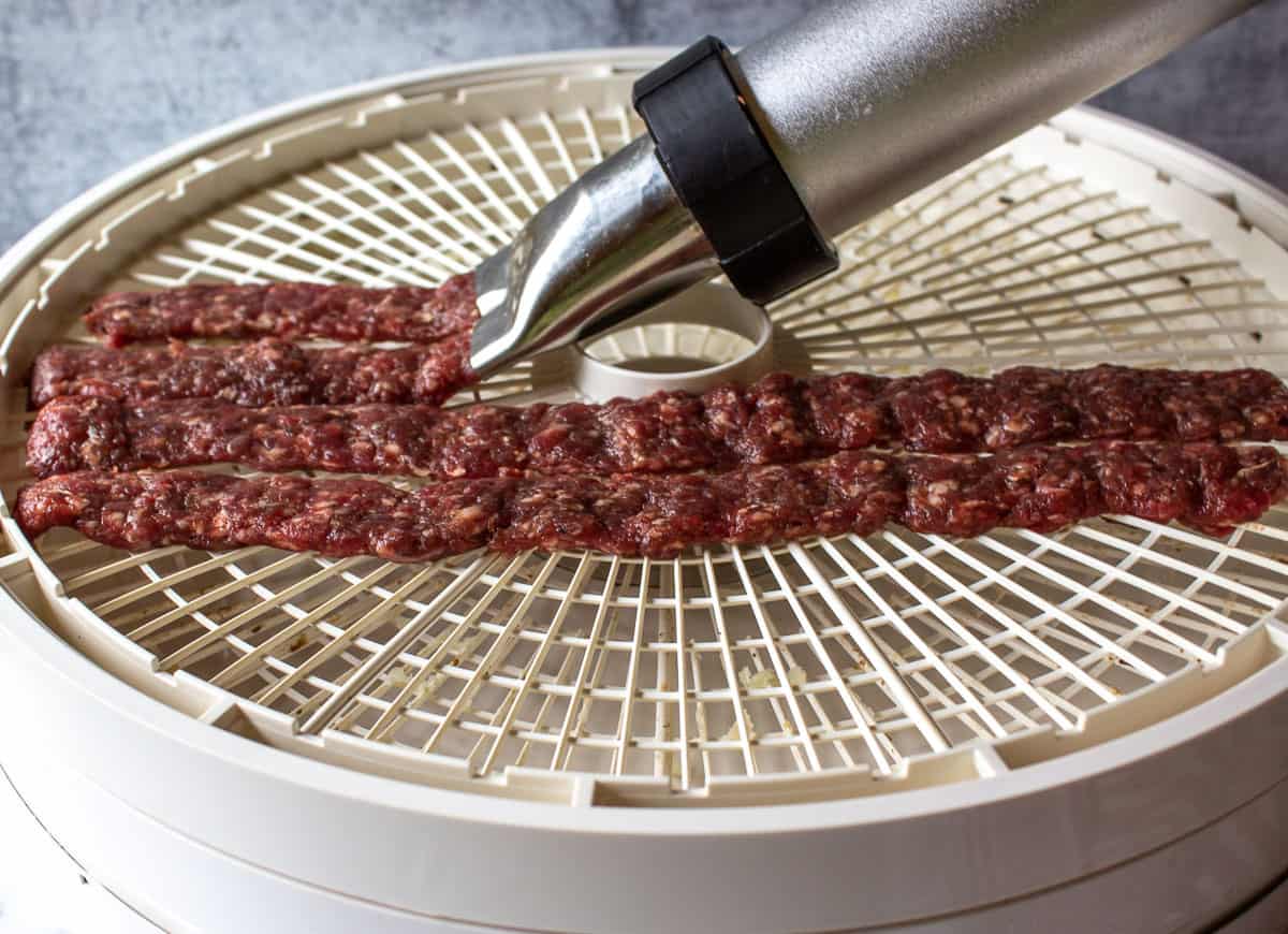 Squeezing our ground venison onto a dehydrator tray.