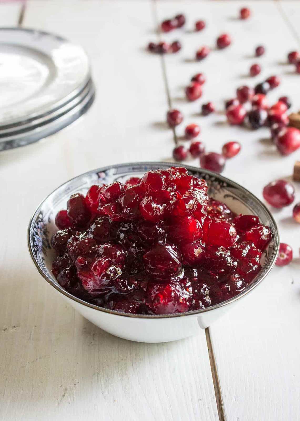 A small dish filled with cranberry sauce and fresh cranberries behind the dish.