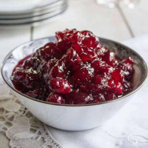 Cranberry sauce in a white china dish on top of a white napkin.