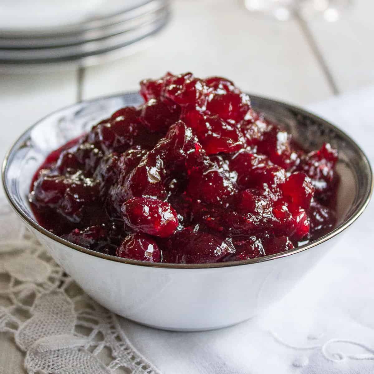 Cranberry sauce in a white china dish on top of a white napkin.