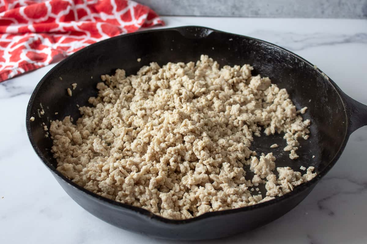 A black pan filled with cooked ground chicken.