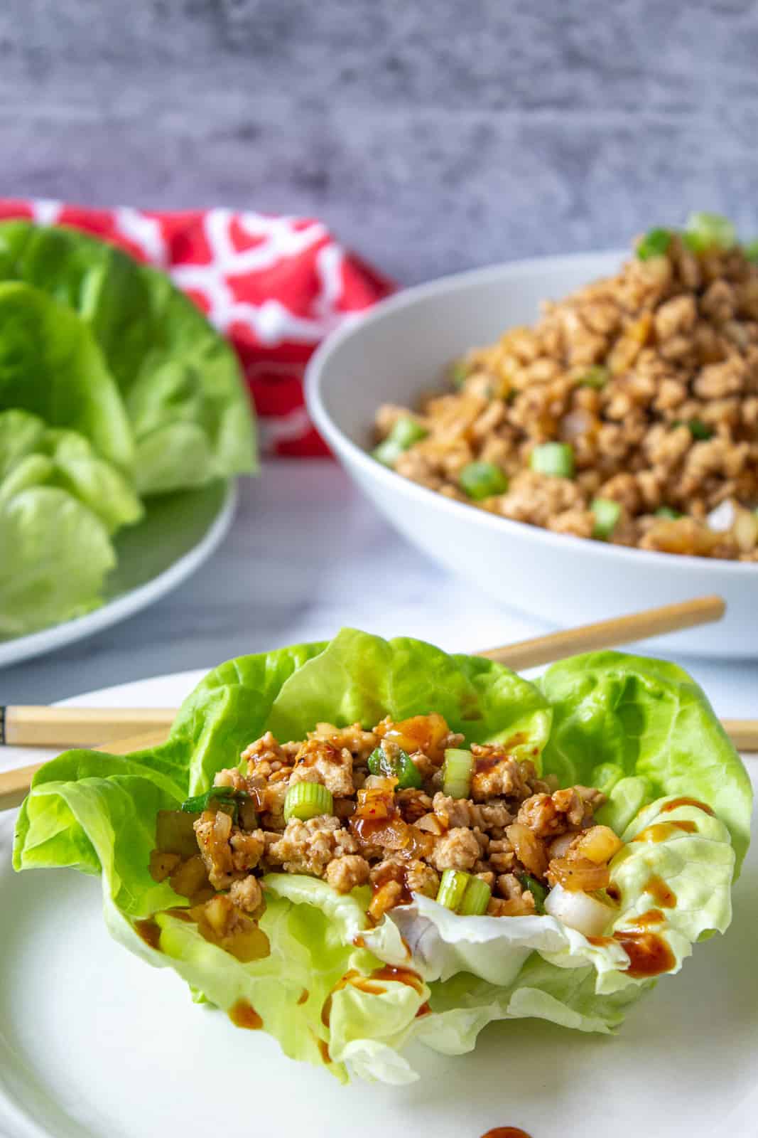 A lettuce leaf filled with chopped chicken and drizzled with a brown sauce.