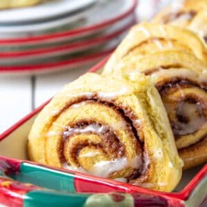 Cinnamon rolls stacked in a red and green dish.