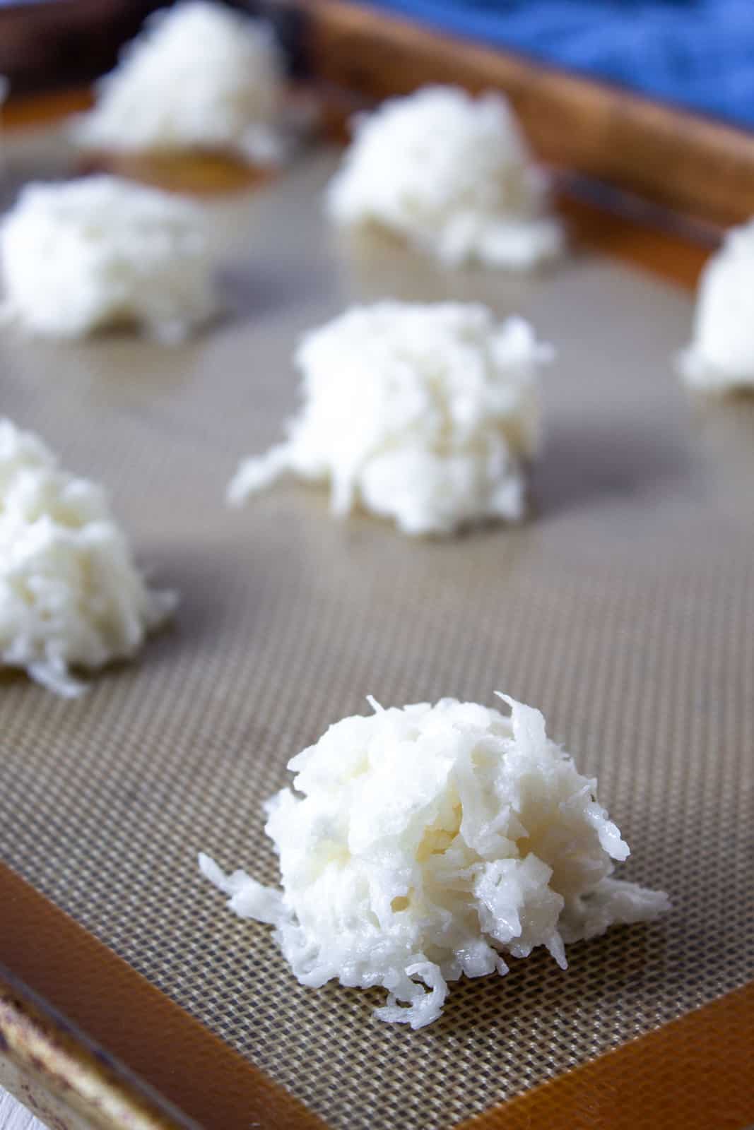 Balls of coconut on a baking sheet.