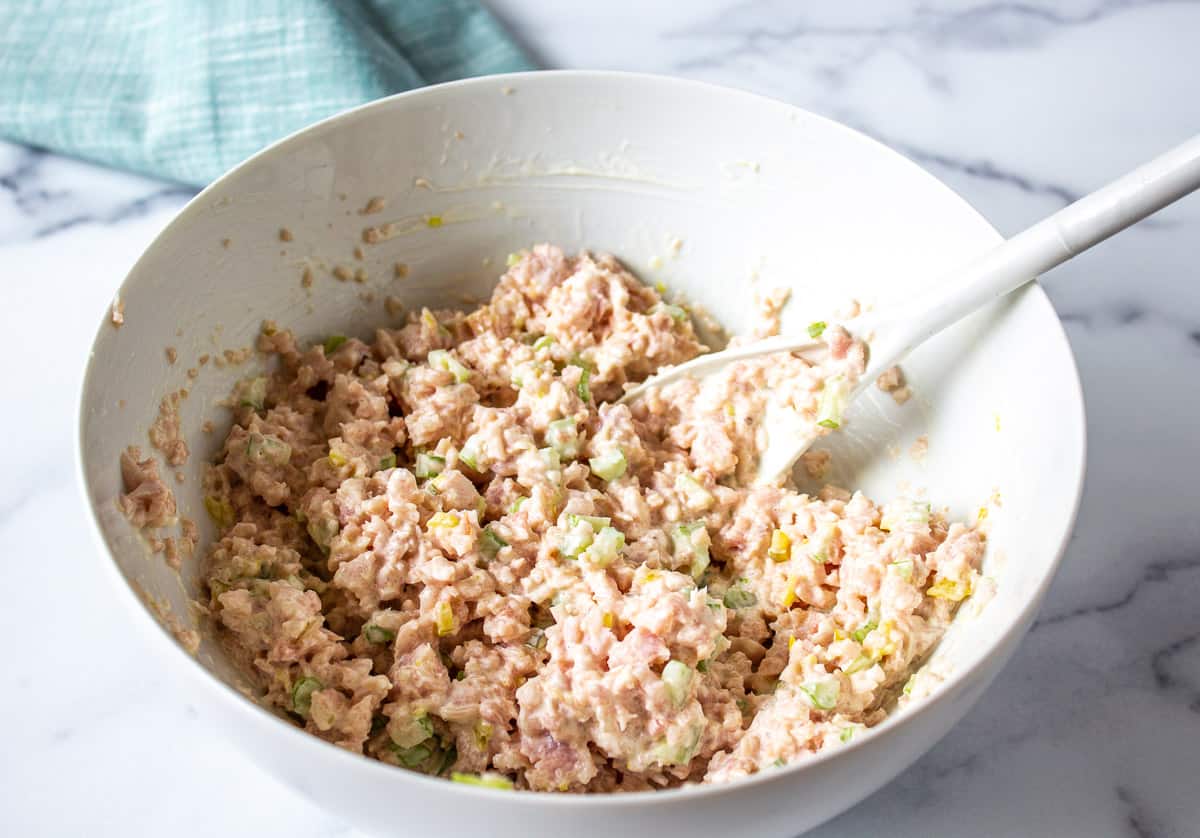Deviled ham salad in a white bowl with a mixing spoon.