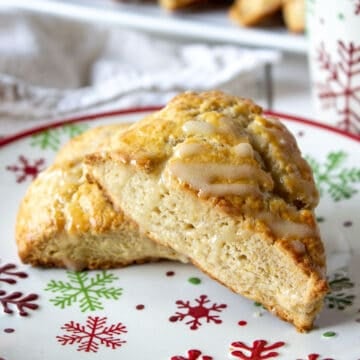 Two triangular scones topped with a glaze on a holiday plate.