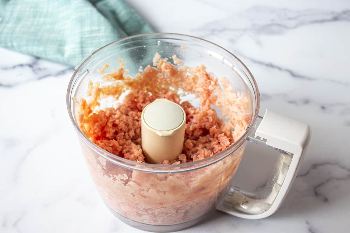 Finely chopped ham in a food processor bowl.