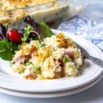 A plate filled with a rice and ham casserole with a green salad next to the casserole.