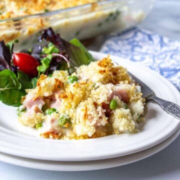 A plate filled with a rice and ham casserole with a green salad next to the casserole.