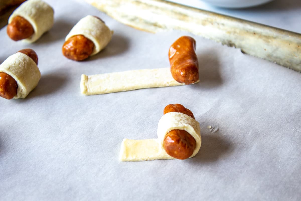 Little smokies being wrapped up into puff pastry dough.