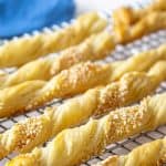 Twisted bread sticks topped with sesame seeds on a baking rack.
