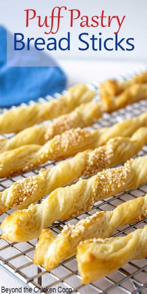 Twisted bread sticks topped with sesame seeds on a baking rack.
